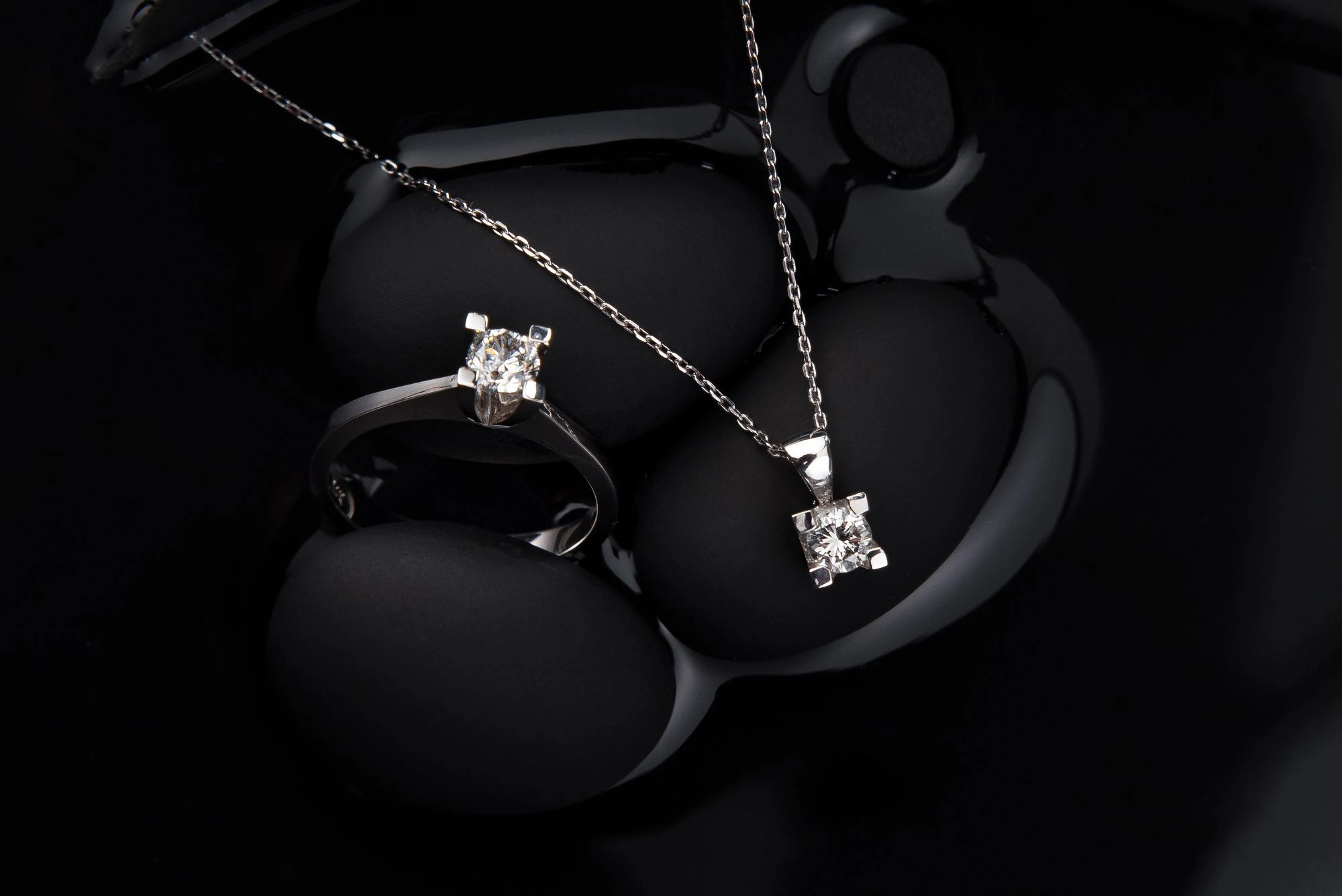 Diamond pendant necklace and ring on black velvet jewelry display
